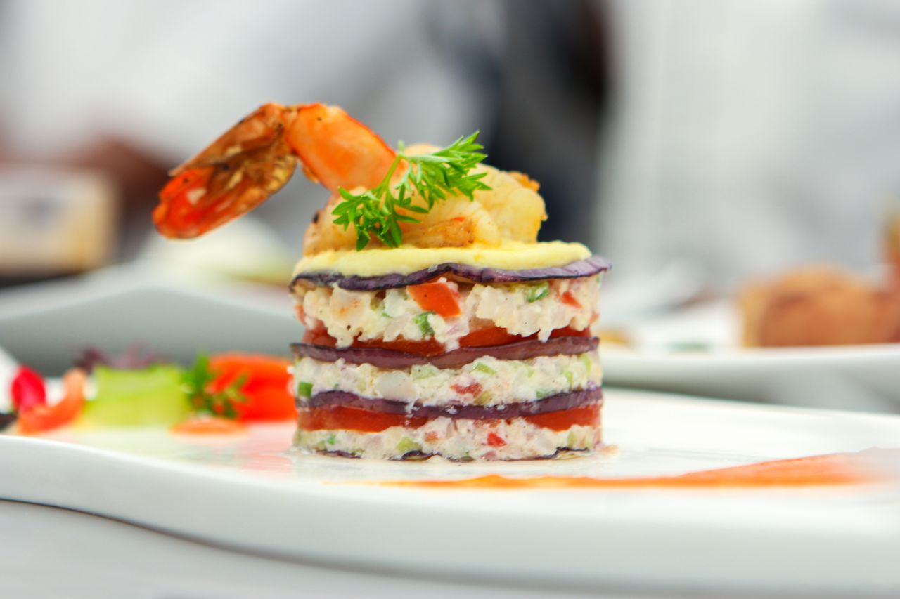 Delicate layers of shrimp, vegetables, and garnish create a gourmet culinary masterpiece.