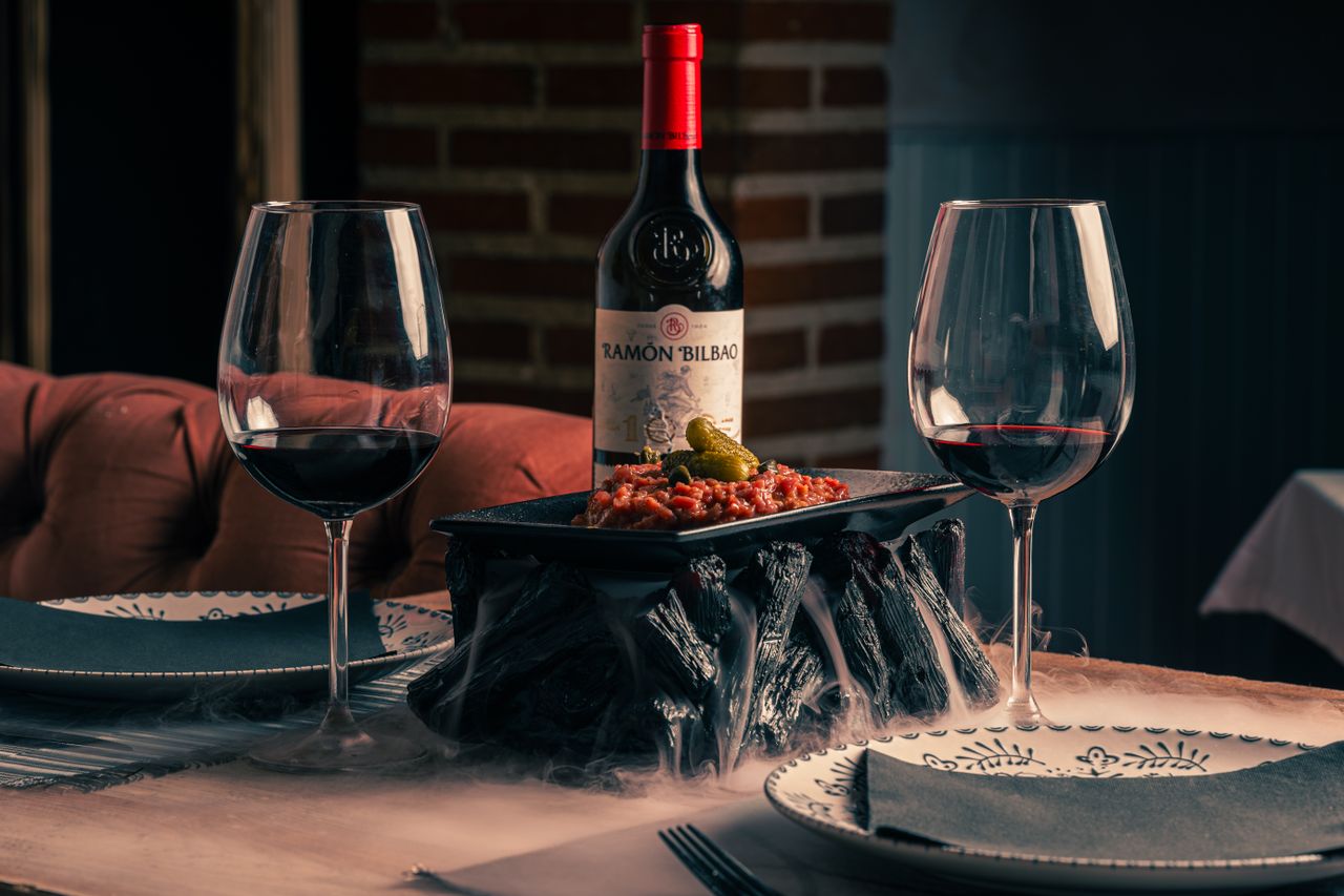 Cozy dining table with red wine, appetizers, and stylish dinnerware, perfect for a romantic evening.